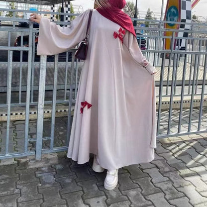 This flowing abaya is designed with delicate bow accents that add a playful yet elegant charm.