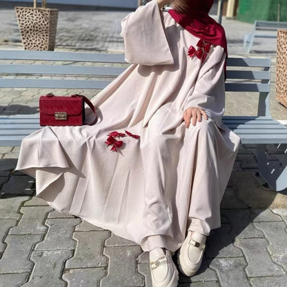 This flowing abaya is designed with delicate bow accents that add a playful yet elegant charm.