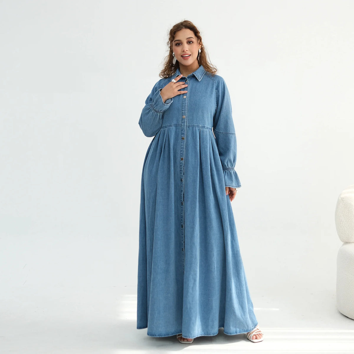 Woman wearing a long blue denim dress on a white background