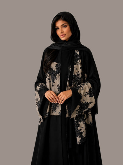 Anab Abaya 2-piece set featuring a black flowing dress with beige floral patterned panels and a matching black hijab.
