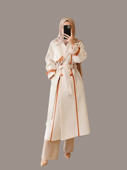 Anab Abaya elegant cream belted coat with brown contrast trim, lapel collar, and tailored fit worn by a woman.